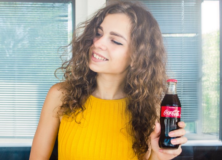Femme aux longs cheveux bouclés et à la Coca-Cola