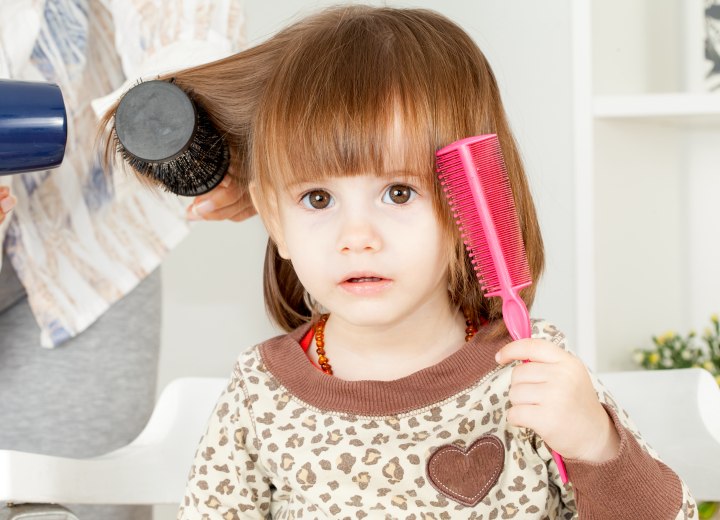 Lisser les cheveux d'un enfant avec un fer à lisser et alopécie du peigne  chaud des enfants