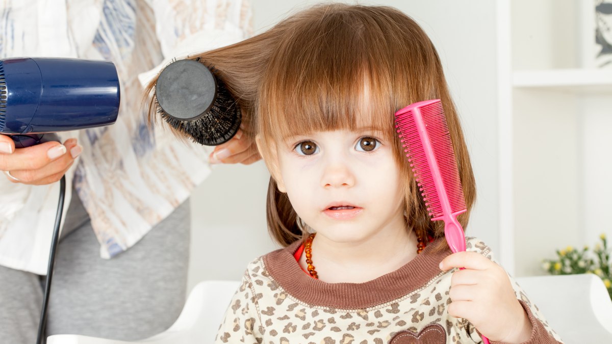 Lisser les cheveux d'un enfant avec un fer à lisser et alopécie du peigne  chaud des enfants